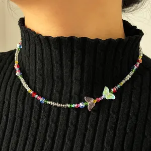 Détail d'un collier de perles colorées avec papillon porté sur un col roulé noir