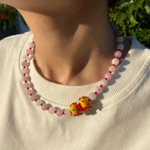 Gros plan d'un collier ras du cou en perles roses avec pendentif en verre jaune sur modèle