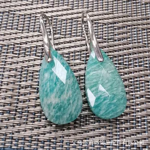 Macro detail of faceted green teardrop gemstone earrings with elegant silver hooks