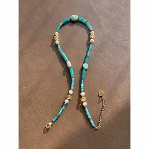 Detail view of natural stone beaded necklace with pearls and turquoise stones