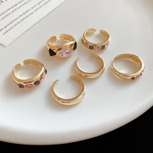Set of elegant gold-colored irregular geometric open rings featuring pink and purple crystals