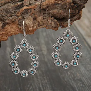 Gros plan des motifs floraux turquoise et de la texture en argent antique des boucles.