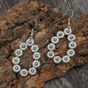 Gros plan de boucles d'oreilles gouttes avec marguerites turquoise sur fond d'écorce rustique