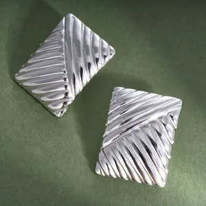 Close-up of silver titanium steel rectangular earrings with diagonal ribbed pattern