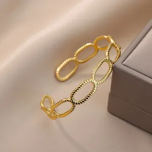 Detailopname van de 18K vergulde roestvrijstalen open armband met getextureerde schakels