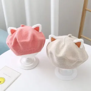 Close-up view of pink and beige children's knitted berets featuring adorable plush cat ears