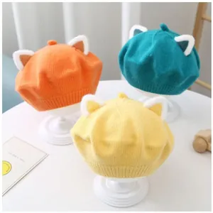 Detailed shot of three colorful kids' knitted berets with cute plush ears