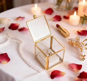 Detail of elegant mini glass jewelry box with gold frame and velvet ring cushion in romantic setting