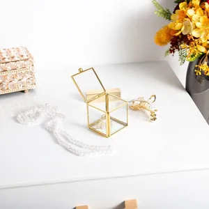 Close-up of a mini gold-framed glass jewelry box displayed on a white vanity table