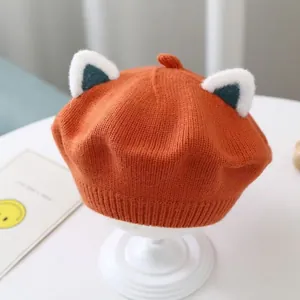 Close-up of cute orange kids knitted beret hat with fox ears for autumn winter