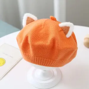 Detailed macro view of an orange knitted baby beret featuring cute plush animal ears.