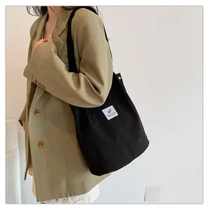 Dettaglio di borsa tote in velluto a coste nera portata da una modella elegante