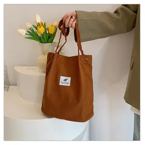 Dettaglio di un'elegante borsa tote in velluto a coste marrone tenuta da una persona