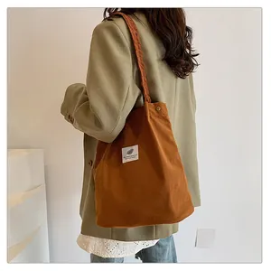 Dettaglio di una borsa tote in velluto a coste marrone con tessuto materico ed etichetta