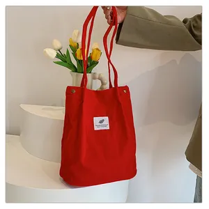 Borsa tote in velluto a coste rossa su sfondo minimalista con tulipani