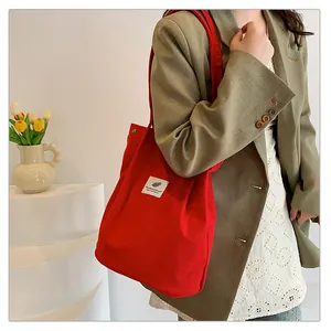 Borsa a tracolla in velluto a coste rosso con dettaglio della trama e etichetta ricamata.