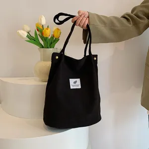 Dettaglio della borsa a tracolla in velluto nero portata a mano in un set minimalista