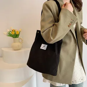 Dettaglio della borsa shopper in velluto a coste nero con toppa decorativa bianca
