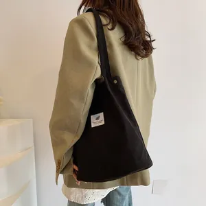 Borsa tote in velluto a coste nero stile artistico indossata da una modella in studio