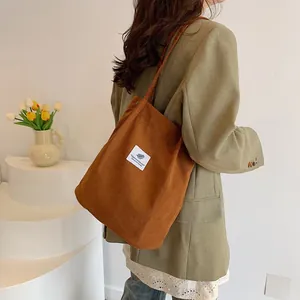 Elegante borsa a tracolla in velluto a coste marrone indossata da una modella chic