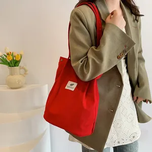 Borsa tote in velluto a coste rosso capiente mostrata in un dettaglio di stile unico