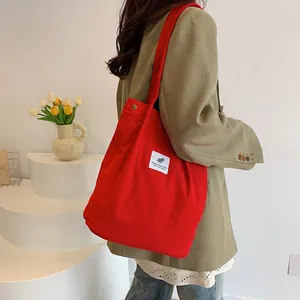 Primo piano di una borsa tote in velluto a coste rosso indossata sulla spalla