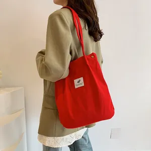 Borsa a spalla in velluto a coste rossa indossata da una persona in abito casual