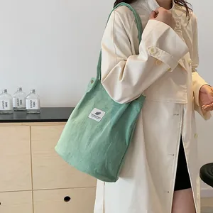 Modella con borsa a tracolla in velluto a coste verde chiaro in un ambiente interno elegante.