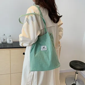 Borsa a spalla in velluto a coste verde da donna con trench beige