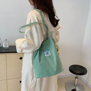 Modella con borsa a tracolla in velluto a coste verde dal design molto minimalista