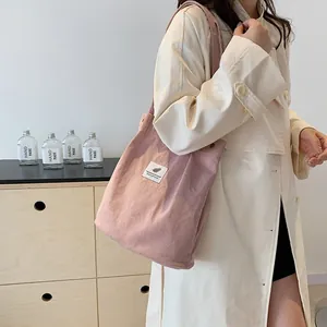 Borsa a tracolla in velluto a coste rosa indossata da una modella in trench