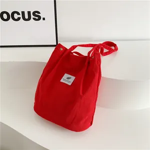 Borsa tote in velluto a coste rosso con etichetta minimalista su sfondo bianco pulito