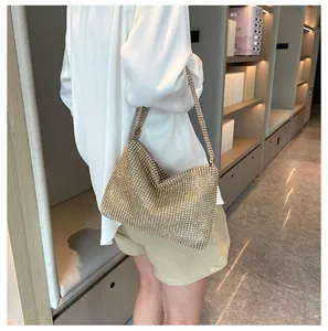 Elegante bolso de mano con pedrería dorada para mujer llevado al hombro en una tienda