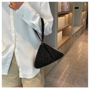 Primer plano de un bolso de mano triangular con pedrería negra llevado por una modelo