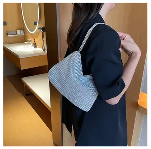 Vista detallada del bolso de mano con pedrería plateada llevado al hombro con estilo.