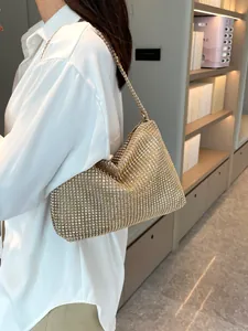 Elegante bolso de hombro de diamantes de imitación dorados combinado con camisa blanca.
