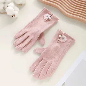 Close-up detail van roze winterhandschoenen met geborduurde bloem en decoratieve parel