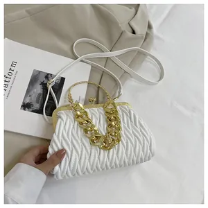 Dettaglio di elegante borsa a mano bianca a pieghe con catena dorata e chiusura vintage.