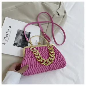 Dettaglio borsa a tracolla plissettata rosa con manico a catena d'oro e chiusura a scatto