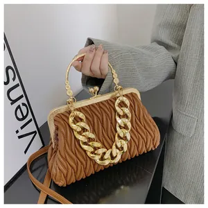 Dettaglio di una borsa marrone arricciata con catena dorata e chiusura in metallo.