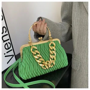 Dettaglio borsa a mano verde brillante a pieghe con catena dorata tenuta da modella