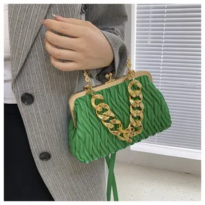 Dettaglio di una borsa a mano plissettata verde vivace con catena dorata e chiusura a scatto