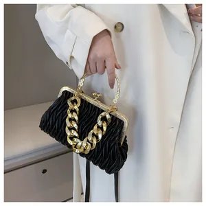 Dettaglio della borsa a tracolla nera plissettata con catena d'oro e chiusura vintage