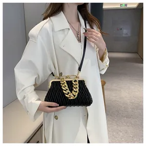 Elegante borsa a mano nera plissettata con catena dorata abbinata a un cappotto bianco