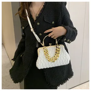 Vista dettagliata di una borsa a mano bianca a pieghe con manico a catena dorata