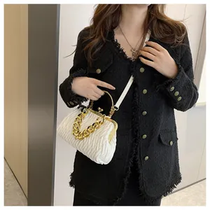 Primo piano di una borsa a mano plissettata bianca con catena d'oro e chiusura su giacca nera