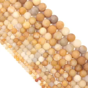 Vue macro de perles de jade jaune mat de tailles variées pour bijoux à faire soi-même