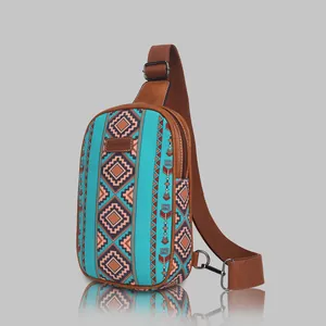 Detailed view of turquoise canvas chest bag with ethnic diamond pattern and brown strap