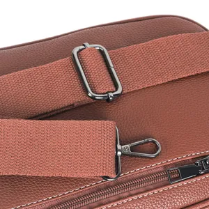 Detail view of brown leather bag strap with dark metallic adjustable buckle and clasp.