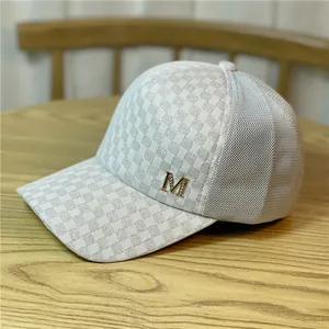 Vista detallada de gorra de béisbol de malla a cuadros plateados con logo M brillante